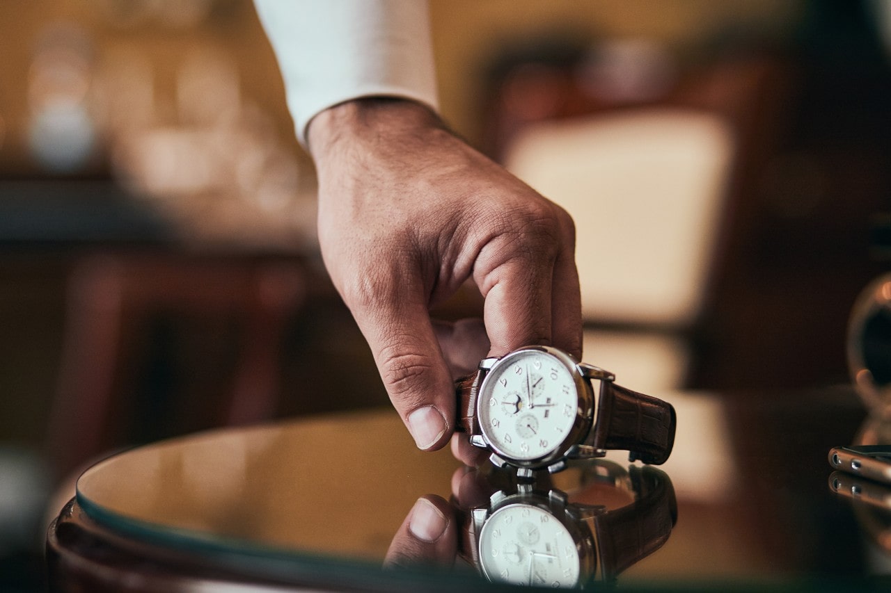 Image of a hand picking a watch up off of a round table