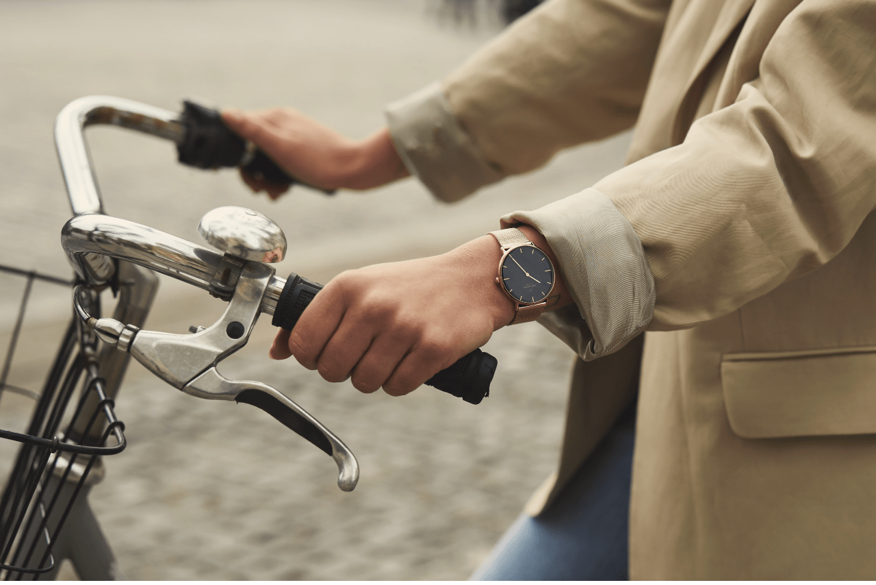 Hands holding bike handle bars with a gold watch on the left wrist