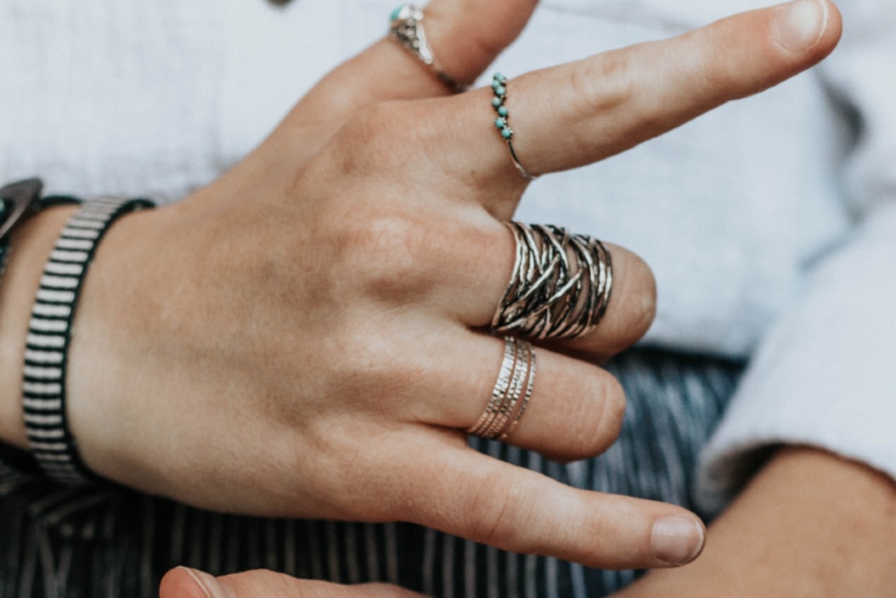 A person wearing multiple styles of rings across four fingers