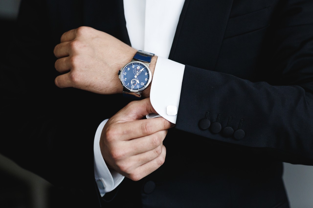A man adjusts his cufflink while showing off his timepiece