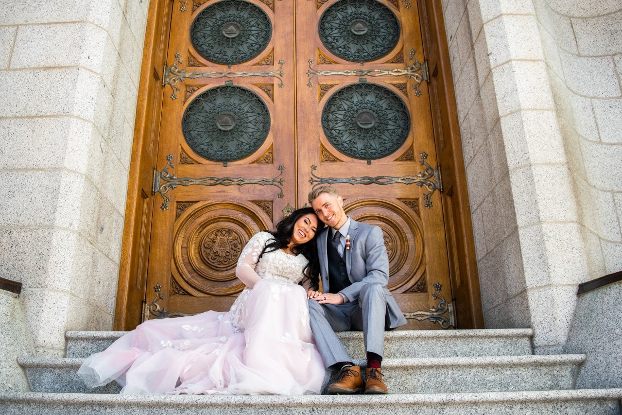 A couple snuggles together on the steps of their wedding chapel before their wedding