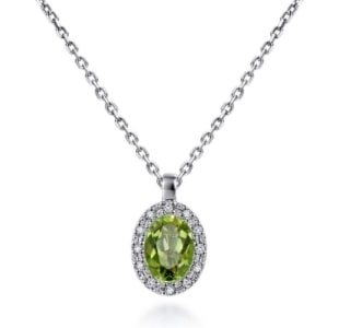 A solitaire necklace with a silver cable chain features an oval cut peridot