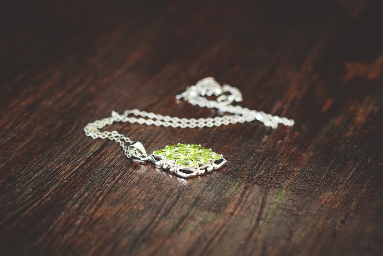 A peridot silver pendant sits on a wooden floor